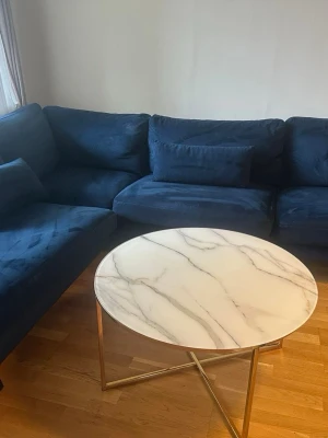 Soffa  och vardagsrumsbord - Säljer en Copenhagen 2,5-sits L-soffa i sammet, köpt på Trademax. Soffan är rymlig och bekväm med som passar perfekt i vardagsrummet.  Soffan är köpt på Trademax och ordinarie pris är 12,500kr. Soffbordets ordinarie pris är 1520kr. Behöver få sålt på de så fått så möjligt på grund av att ska flytta ut härifrån!  Säljes på grund av flytt. Fint och elegant soffbord med marmormönster och guldfärgade detaljer. 80 cm runt och passar perfekt i vardagsrummet. Säljes på grund av flytt.