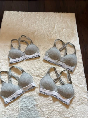 4 st Grå Calvin Klein BH:ar - Säljer 4styckrn gråa bhar från Calvin Klein med vit resår och logga. Bh:n har vadderade kupor och brottarrygg i mjukt stretchigt material. Storlek xs, använda men utan hål eller liknande 