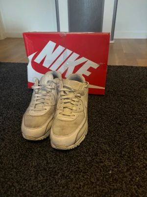 Nike Air Max 90 vita sneakers - Snygga vita Nike Air Max 90 sneakers med klassisk siluett och synlig Air-enhet i sulan. Skorna har ovandel i mesh och läder för både stil och komfort. Perfekta för dig som gillar streetwear och vill ha en ikonisk sneaker i garderoben.