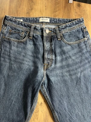 Blå relaxed jeans från Jack & Jones - Säljer ett par blå jeans från Jack & Jones i modellen Relaxed/Chris. Klassisk femficksdesign, raka ben och kontrastsömmar. Jeansen är tillverkade i denim och har en avslappnad passform som är perfekt för en chill stil. 105 cm långa från midjan till längst ner på jeansen