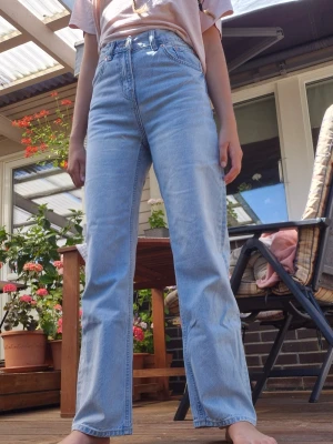 Ljusblå raka high waist jeans - Säljer ett par ljusblå jeans med hög midja och raka ben. Aldrig använd. Klassisk femficksmodell med knapp och dragkedja framtill. Jeansen har en avslappnad passform och är tillverkade i ett mjukt denimtyg. Perfekta för en chill och trendig look.