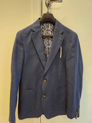 Kostymset i linne från Dressmann  - Dressmann blå blazer, storlek 50 regular Slim fit. Aldrig använd. Se bild för mått. Säljes då den nu är för liten och inte kommer användas. Dressmann mörkblå byxor, storlek 32/30. Oanvända. Prislapp kvar. Säljes då dem är för små och aldrig kommer användas.