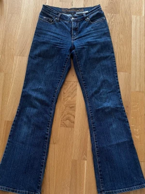 Blå bootcut jeans från Street One - Snygga blå bootcut jeans från Street One med klassisk femficksmodell och kontrastsömmar. Jeansen har normal midja och är tillverkade i slitstark denim med lätt utsvängda ben. Perfekta för en avslappnad och trendig look.