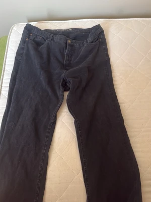 Svarta raka jeans från April Denim - Säljer ett par svarta jeans från April Denim med rak passform och klassisk femficksdesign. Jeansen är tillverkade i ett hållbart denimtyg och har knappgylf samt bälteshällor. Perfekta för en avslappnad och stilren look.