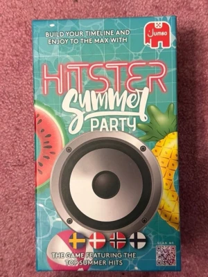 Hitster Summer Party sällskapsspel - Hitster Summer Party är ett färgglatt sällskapsspel med musiktema där du bygger en tidslinje med sommarhits. Lådor i blått med mönster av vattenmelon och ananas. Innehåller QR-koder för att spela låtar direkt i Spotify. Perfekt för musikälskare och spelkvällar.