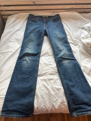 Blå bootcut jeans Superlow 26-32 Levi’s  - Säljer ett par blå bootcut jeans i modellen Superlow boot från Levi’s. Storlek 26-32. Jeansen har klassisk femficksdesign och dragkedjegylf. Perfekta för dig som gillar en avslappnad men ändå snygg stil. Jeansen är köpta direkt från NK i Göteborg och kvitto finns. Använda flera gånger men i topp skick. Nypris 949 kr, mitt pris 499 kr. 
