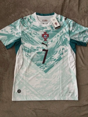 Cristiano Ronaldo Portugal jersey #7   - Snygg Portugal fotbollströja från Puma med nummer 7 och Ronaldo på ryggen. Tröjan är mintgrön med vitt och har ett vågigt mönster, korta ärmar och rund hals. Tillverkad i lätt och ventilerande material med DryCell-teknologi.