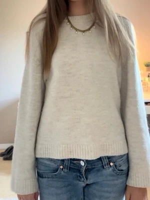 Beige stickad tröja Gina Tricot - Mysig beige stickad tröja från Gina Tricot. Tröjan har rund halsringning, långa ärmar och ribbade muddar vid ärmslut och nederkant. Perfekt för lager på lager och enkel att matcha med jeans.