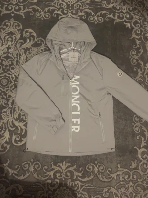 Grå vindjacka från Moncler - Snygg grå vindjacka från Moncler med stor vit logga framtill. Storlek S men passar också bra med M