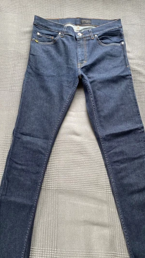 Mörkblå slim fit jeans - W32 L32!!! Snygga mörkblå slim fit jeans med klassisk femficksdesign och kontrastsömmar. Jeansen har normal midja och raka ben, tillverkade i stretchigt denimtyg för en bekväm passform. Perfekta för en trendig och avslappnad look.