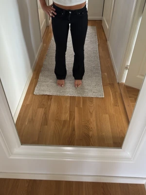 Svarta bootcut jeans - Säljer ett par svarta bootcut jeans med klassisk femficksmodell och normal midja. Jeansen har utsvängda ben och är perfekta för dig som gillar en tidlös och trendig look. Materialet är denim med lite stretch för extra komfort.