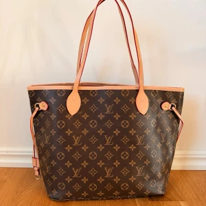Brun handväska trendig och klassisk Monogram väska med matchande clutch  - Säljer en klassisk brun handväska i brunt monogrammönster med beigea detaljer och handtag. Väskan har öppen topp, sidoremmar och kommer med en matchande clutch. Perfekt för dig som gillar lyxig och tidlös design.