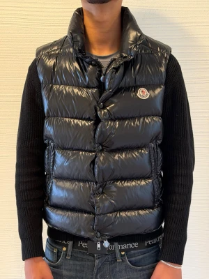 Moncler Tib Gilet – Svart – Strl 2 - Säljer en Moncler Tib Gilet i svart, storlek 2 (motsvarar S). En av Monclers mest eftertraktade och ikoniska dunvästar.  ✅ 100 % äkta kan köpas på min vinted (leoo80) för vinteds egna artikelverifierng ✅ Mycket fint skick ✅ Storlek 2 (S)  Nypris: ca 11 000–13 000 kr  Mitt pris: 5 299 kr  Säljs utan kvitto, kartong eller övriga tillbehör. Endast västen ingår.  Skicka gärna ett meddelande vid intresse eller om du vill ha fler bilder.