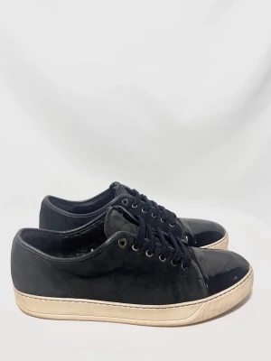 Lanvin Cap Toe Sneakers  - Lanvins i en populär model med glansig framtå! Okej skick men de har mycket kvar att ge! 6,5/10, mockan är sliten och finns märken på framtån, men inget som märks speciellt mycket vid använding. Uk 12 passar 46. Färgen är svart/marinblå. Kontakta mig för fler frågor och funderingar!