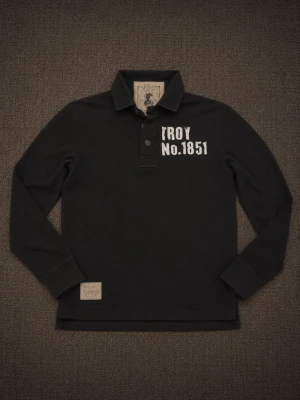 Svart henley med tryck 2000s vintage abercrombie style - Svart långärmad henley med vit texttryck fram och bak. Skjortan har krage, knappar vid halsen och detaljer som 'TROY NO.1851' på bröstet samt tryck på ryggen. Tillverkad i mjukt bomullstyg, perfekt för en avslappnad streetwear-look.
