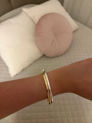 Tvåfärgat metallarmband - Snyggt armband i både guld- och silverfärgad metall. Designen är enkel men trendig med två smala, sammanlänkade band som ger en cool och stilren look. Perfekt accessoar för att lyfta vilken outfit som helst.