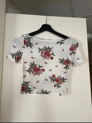 Blommig croppad T-shirt - Blommig croptop från H&M. Skulle rekommendera den för de som brukar ha XS. Mycket bra skick!