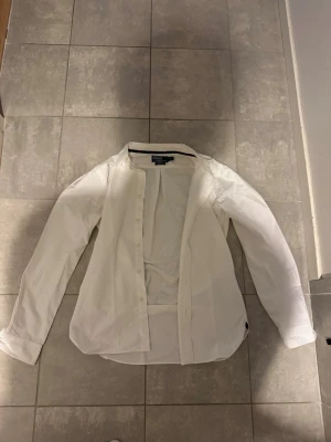 Vit skjorta från Polo Ralph Lauren - Klassisk vit skjorta från Polo Ralph Lauren i slim fit-modell. Skjortan har långa ärmar, knappar framtill och en stilren design som passar till många olika looks. Tillverkad i mjuk bomull för en bekväm känsla. Storlek S