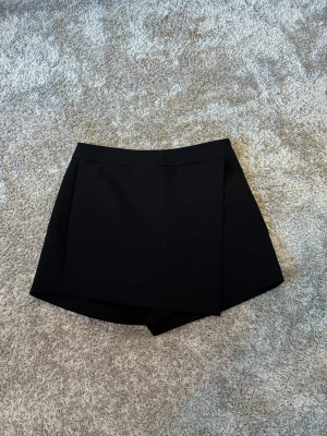 Svart omlott kortkjol/shorts -  svart kortkjol med omlottdesign framtill. Bak är det shorts. Väl använd, därav nopprig mellan benen (sista bilden). Från Gina Tricot  i XS❤️