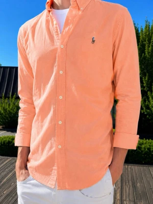 Persikofärgad skjorta från Ralph Lauren - (Moddelen är 185 och väger 75kg)Säljer en persikofärgad skjorta från Ralph Lauren med klassisk button-down krage och broderad logga på bröstet. Skjortan har långa ärmar, knappar framtill och är tillverkad i mjuk bomull. Perfekt för en avslappnad men stilren look.