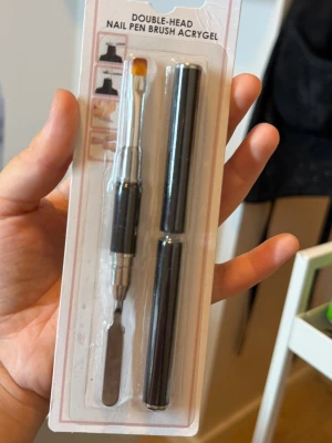 Nagelborste + nagelbandspusher  - Säljer en dubbeländad nagelpenna  med borste på ena sidan och nagelsbands pusher på andra. Färgen är svart och silver, och materialet är metall och syntetborst. Perfekt för att forma och applicera gel på naglarna. Helt ny. 