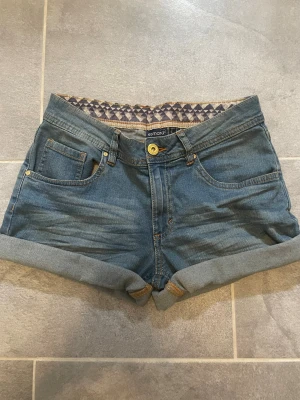 Blå denimshorts från esmara - Snygga blå denimshorts från esmara med klassisk femficksdesign och uppvikta benslut. Shortsen har bälteshällor, knapp och dragkedja framtill samt dekorativa sömmar på bakfickorna. Perfekta för varma dagar!