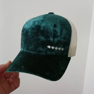 Grön vit velvet keps - Säljer en vit och grön keps som är köpt från hatstore i velvet matrial. Den är i nyskick och bara använd ett fåtal gånger. 