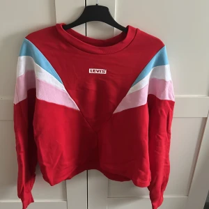 Levis sweatshirt - Croppad, röd levis sweatshirt. Bra skick, använd endast ett fåtal gånger. Finns hål längst ner där ett snöre brukade sitta, men är inte så synliga. 