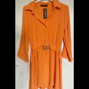 Från Boohoo Orange skjortklänning med bälte Säljer för att jag tyckte den var för kort, aldrig använd😇 Nypris var 450kr
