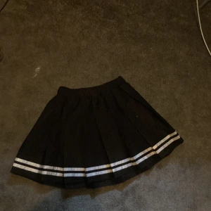 Kjol - Svart kjol med vita ränder längs mer. Fint skick aldrig använd 