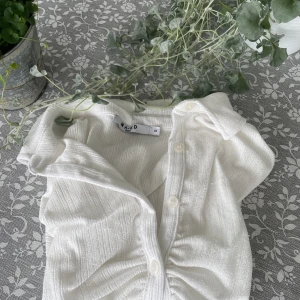 VIT TOPP NAKD - säljer en vit topp i stretchigt material från NAKD med ryschdetalj på kragen 🐚🦋🫶🏼 Använd 1 gång och är i nyskick