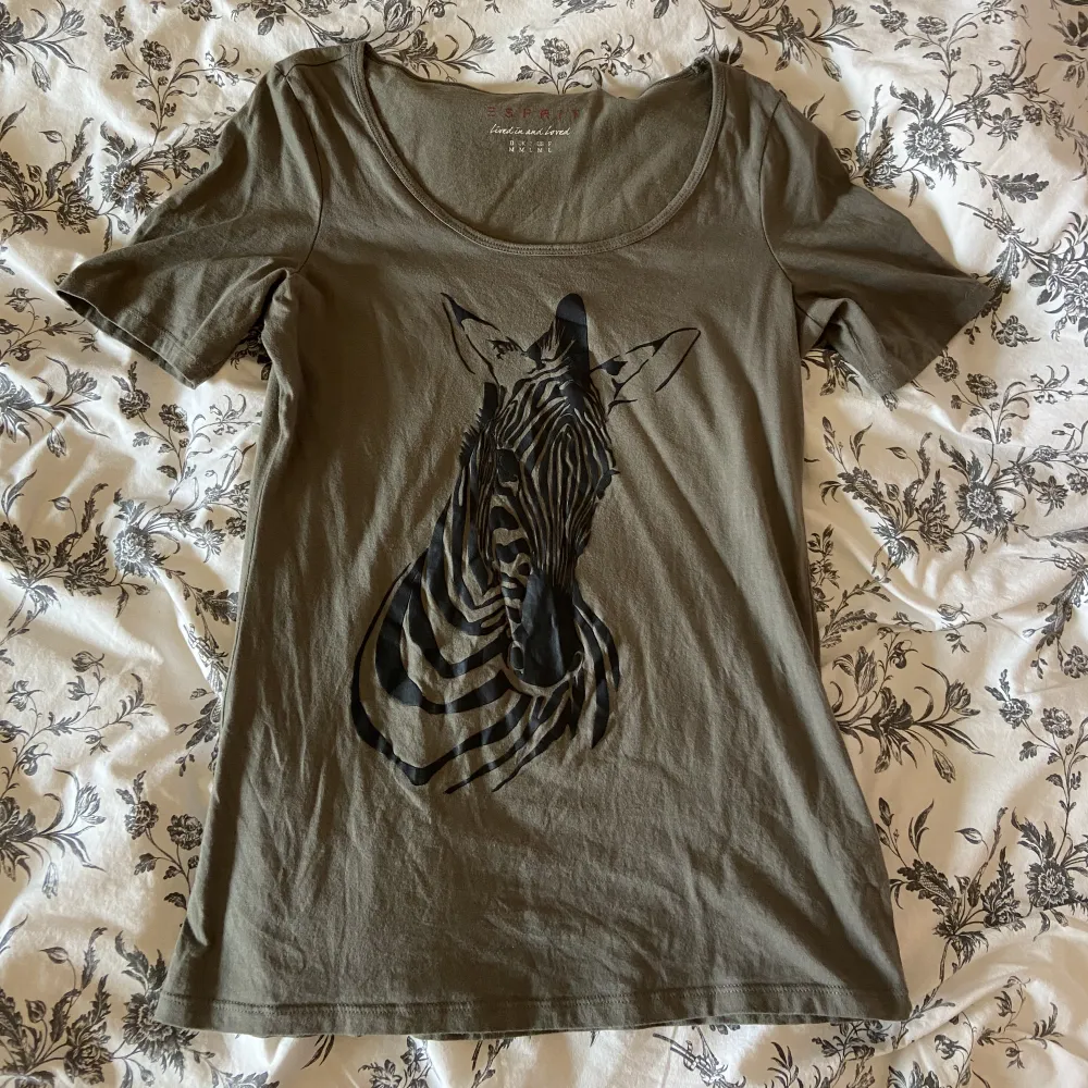 Militärgrön T-shirt med tryck av zebra och en vid urringning. Märke: Esprit. 3 för 2 på allt i min profil 🍓. T-shirts.