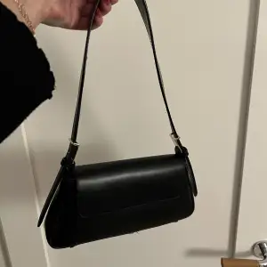 En svart väska från zara med guld detaljer 