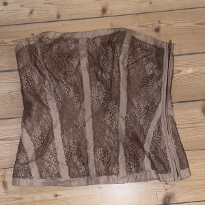 Korsettopp  - Otroligt fin korsettopp i bruna nyanser med pärlor och spets! Stängs med dragkedja i sidan💫Perfekt till fest🪩 Storleken passar en M❣️Bra skick. Skriv vid funderingar och kolla in mina andra annonser💕💕