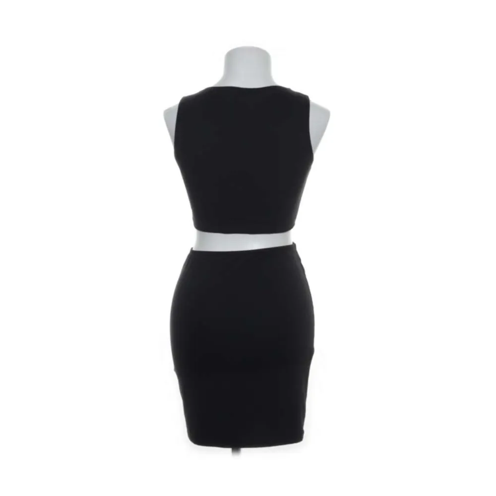 Snygg svart klänning som är delad fast sitter ihop med en rund knytning kan man säga💞. Klänningar.