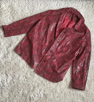 Ormskinn kavaj röd - Supersnygg röd kavaj i tyg med ormskinns-tryck! Köptnpp humana för flera år sedan men jag har aldrig använt den, skulle säga att den är i nyskick. Skriv om ni har frågor!