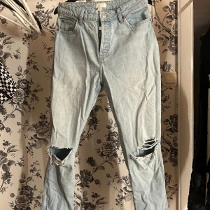 Utsvängda Jeans  - Blåa jeans med hål på knäna och hög midja från HM. Har använt några gånger men skicket är bra. Säljer då jag inte löngre använder dem. 
