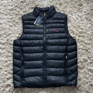 Ralph Lauren väst (helt ny) - Säljer min Ralph Lauren (”the packable gilet”) väst då den är lite stor på mig. Den är helt ny, aldrig använd, med alla tags kvar.   Riktigt fet och passar perfekt att ha under nån jacka som tex en rock/overshirt nu på vintern.   Nypris ca 3300kr. 