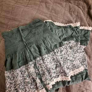 En jätte fin grön kjol som är köpt utomlands!! Den har ett jätte fint mönster och en turkos färg. Man kan andvända den som långkjol men även klänning om man knyter dom vita banden runt halsen! Aldrig andvänd så skicket är som nytt❤
