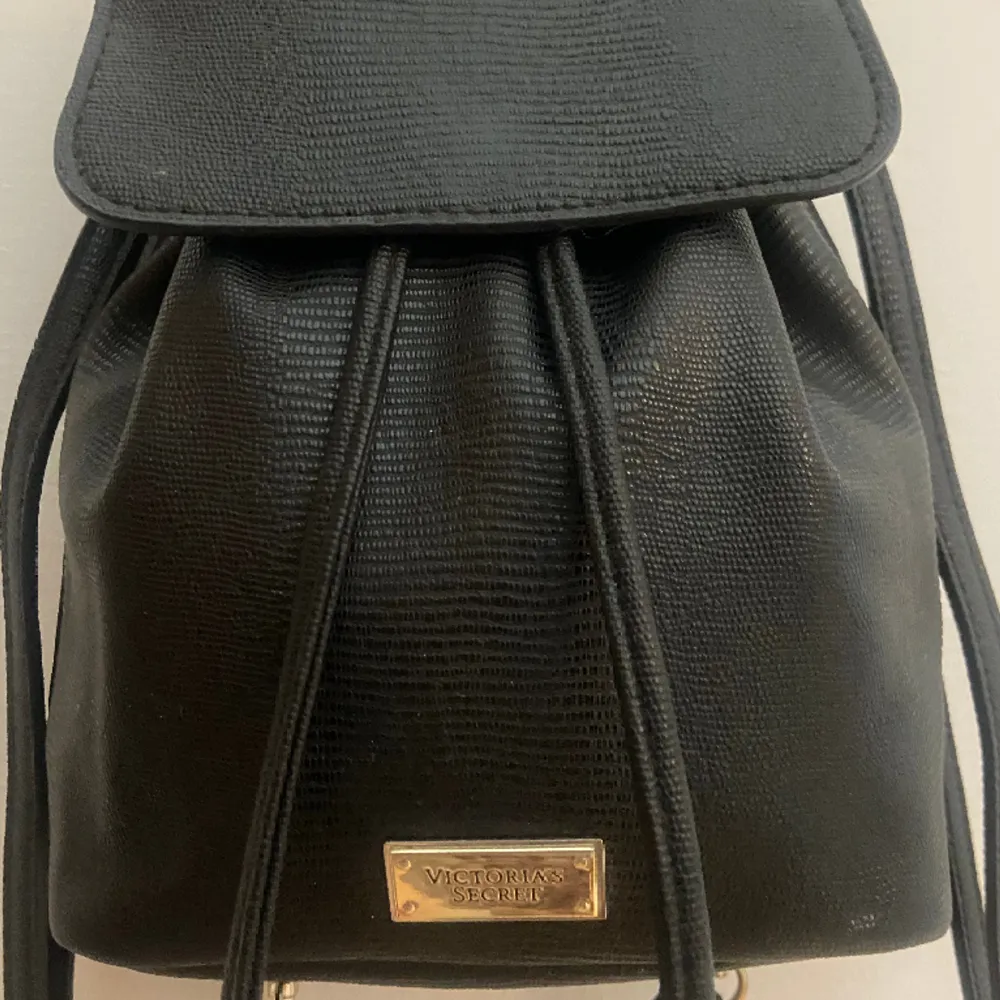 Säljer min vintage victorias secret Victoria Mini  Black Faux Leather Pull Drawstring backpack !! Super gullig mini ryggsäck som är rymlig, och aldrig använd💓 kan skicka fler bilder vid behov!! (Vid bild 3 har jag den över endast en axel). Väskor.