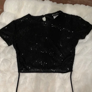 Svart glitter topp öppen rygg - Superfin glittrig svart topp med öppen rygg och snörnig i strl xs!