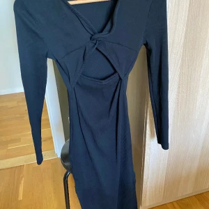 Svart bomullsklänning  - Slits i sidan. Vridning i ryggen. Midilängd.