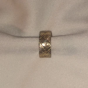 Guld hänge - Guldfärgad fake piercing. Längd ca 1cm. Vikt ca 1g.