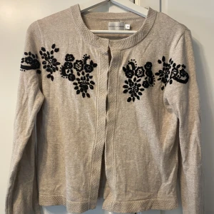 Beige kofta.  - Beige kofta med svarta broderade blommor. Använd endast ett fåtal gånger. Storlek S från Indiska. 