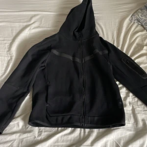 Svart Nike tech fleece zip hoogie - Hej! Säljer denna zip hoodien pågrund av att den är för liten. Den är köpt på Nike, skick 8/10 nypris runt 900. Tveka inte på att höra av er om ni undrar nåt