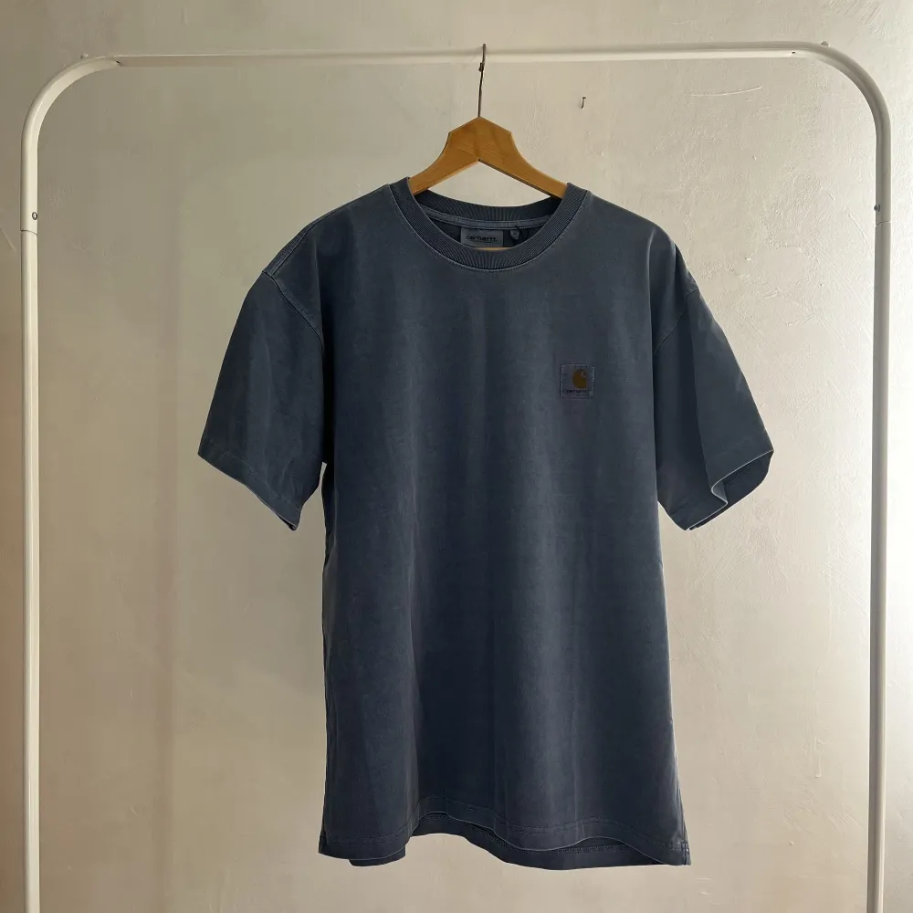 En sprillans ny carhartt tshirt med orginallapparna kvar i urtvättad blå färg. Storlek medium men sitter lite oversized. Storlek Medium. T-shirts.