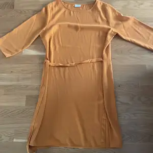 En orange klänning storlek 42 band som man kan dra åt 