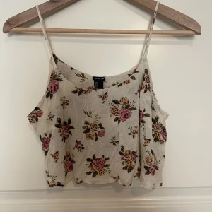 Blommig topp - En gräddvit blommig topp som är köpt från forever 21. Använd ett fåtal gånger och har ett väldigt tunt material