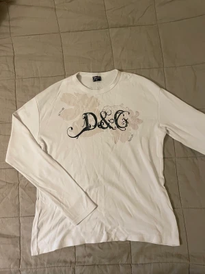 Dolce&Gabbana tröja - Dolce&Gabbana långärmad vit tröja i storlek xxl. Tröjan har tappat några paljetter från trycket men är annars i mycket bra skick! För mer frågor och bilder hör av er i dm!😋