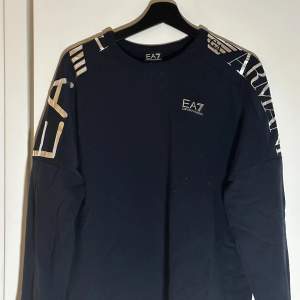 En EA7 tröja i marin blå och silvriga detaljer. Tror att storleken är S/M  Allt tvättas innan det skickas.  
